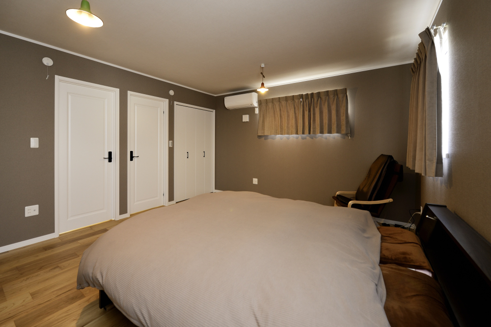 スタイリッシュな壁紙とドアや天井のコントラストがおしゃれな寝室